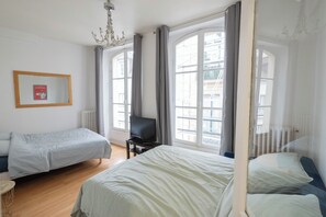 Ein Hotelzimmer mit zwei Betten, einem Fernseher und großen Fenstern mit Vorhängen.