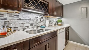 A modern kitchen with dark wooden cabinets, a stainless steel sink, and a tiled backsplash. - Amelia Island 2BR Beach Getaway (Fernandina Beach)