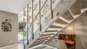A modern staircase with a wooden finish and metal railings, leading to a room with a desk and chair. - Amelia Island 2BR Beach Getaway (Fernandina Beach)