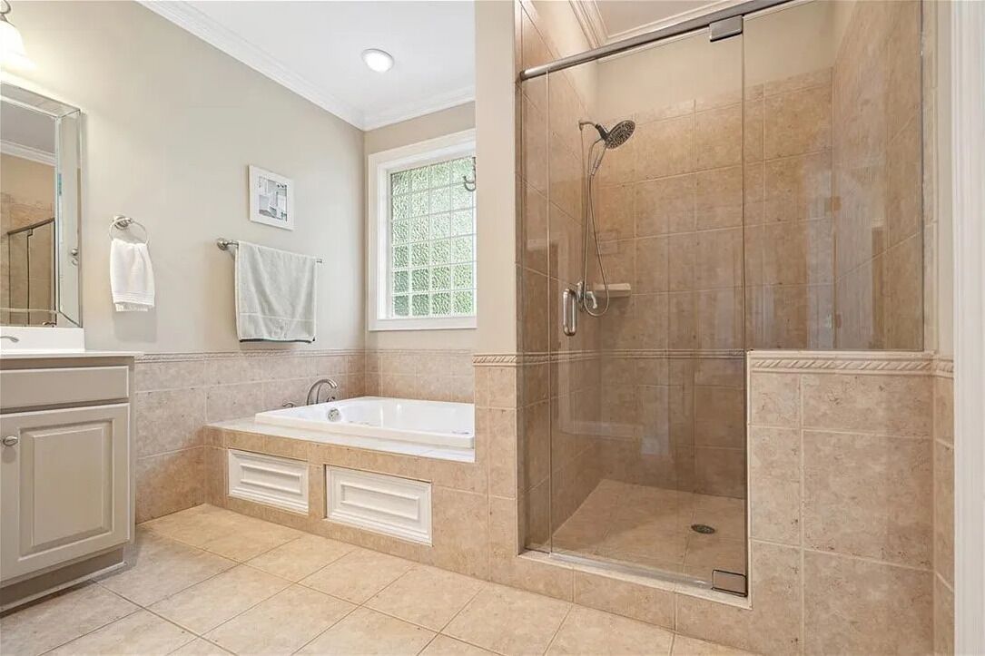 A bathroom with a bathtub, a glass-enclosed shower, and a window with a view.