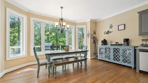A kitchen with a dining table, chairs, a bench, a chandelier, and a cabinet with a coffee theme.