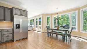 A spacious kitchen with a large island, built-in appliances, and large windows offering a view of the outdoors.