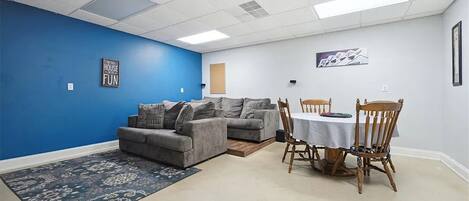 Une pièce avec un mur d’accent bleu, un canapé gris, une table à manger avec des chaises et un tapis.