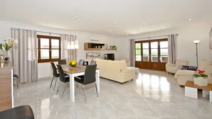 Una sala de estar moderna con comedor, ventanas amplias y un televisor de pantalla plana.