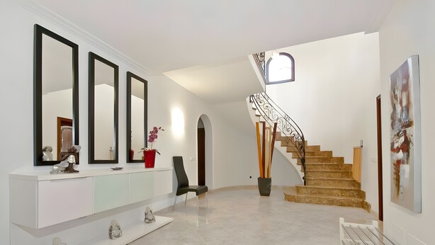 Un interior moderno con una consola blanca, espejos grandes, una escalera y un diseño minimalista.