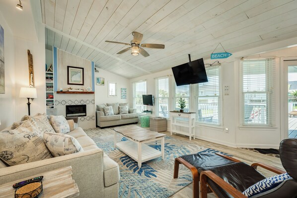 A spacious living room with a ceiling fan, a sofa, a coffee table, and a TV.