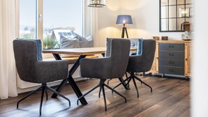 A modern dining area with a wooden table, four grey chairs, a floor lamp, and a cabinet with drawers. - Apartment 'Jost' with Private Terrace, Shared Garden, and Wi-Fi (Sundern)