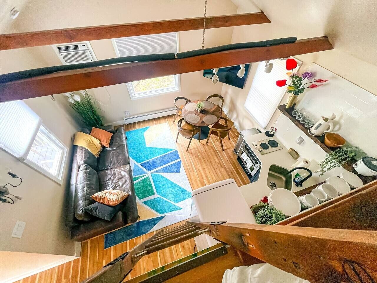 Um interior moderno com uma escada de madeira, sala de estar com sofá e mesa de centro, e cozinha com pia e bancada.