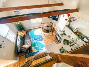 Un intérieur moderne avec un escalier en bois, un espace de vie comprenant un canapé et une table basse, et une cuisine équipée d’un évier et d’un plan de travail.