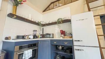 A compact kitchen with a built-in oven, a refrigerator, and a microwave.