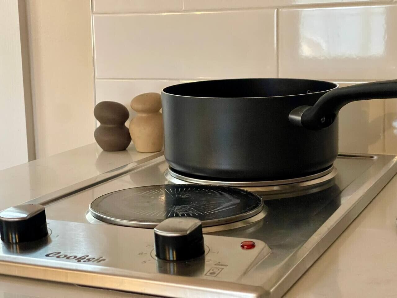 A kitchen with a stove, a pot, and a set of wooden salt and pepper shakers.