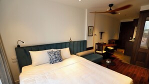 Une chambre d’hôtel avec un grand lit, un bureau et un ventilateur de plafond.
