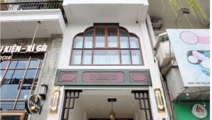 Un immeuble à plusieurs étages doté d’une entrée principale, d’un escalier menant à cette entrée et d’une enseigne au-dessus de l’entrée.