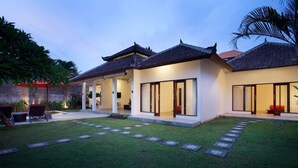 A modern house with a traditional roof, a well-maintained lawn, and a covered patio area.