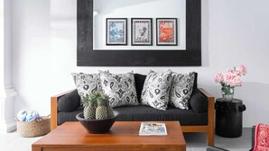 A living room with a black sofa, patterned cushions, a wooden coffee table with a pineapple centerpiece, and a framed picture above the sofa. - Lovely Pool Villa | Short Walk to Potato Head Club (Kerobokan Kelod)