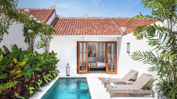 A private pool area with a white building, red-tiled roof, and a small bedroom with a bed and a window. - Lovely Pool Villa | Short Walk to Potato Head Club (Kerobokan Kelod)