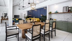 A modern kitchen with a wooden dining table, black chairs, and a blue accent wall.