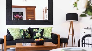 A living room with a black sofa, green patterned pillows, a wooden coffee table, a floor lamp, and a white cabinet. - Chic Villa Bella | Steps from Eat Street Seminyak (Seminyak)