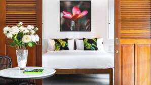A hotel room with a bed, a round table, a chair, and a vase with flowers. - Chic Villa Bella | Steps from Eat Street Seminyak (Seminyak)