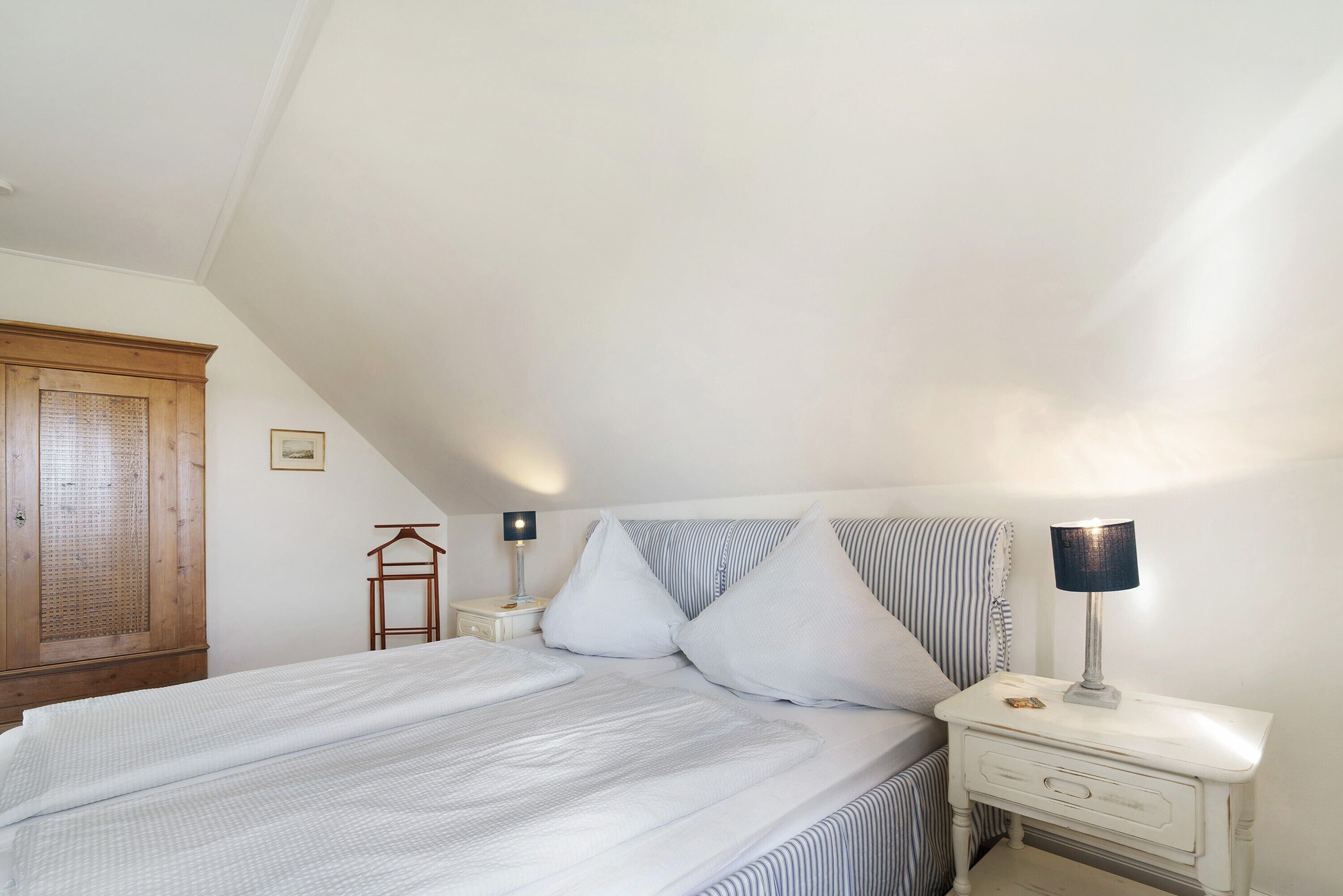 A bedroom with a bed, a bedside table with a lamp, a hanging chair, and a wardrobe.