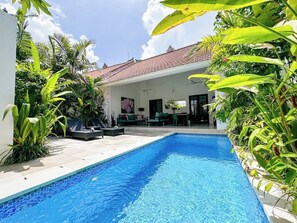 A swimming pool with a tiled deck, surrounded by lush greenery and a covered seating area with a red-tiled roof. - Villa Harris · Walk to Finns, Atlas & Beach (Dalung)