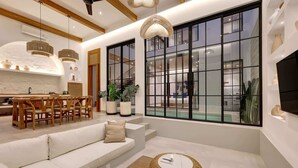 A modern living room with a sofa, dining table, and large windows.