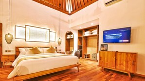 A spacious bedroom with a wooden bed, a wardrobe, and a television on the wall.