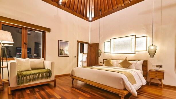 Une chambre spacieuse avec un grand lit, un canapé et un plancher en bois.
