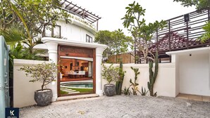A modern house with a pool, potted plants, and a wooden gate.