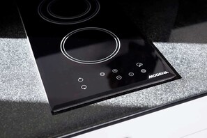 Una cuina de inducció negra amb un panell de control i el nom de marca 'MODENA'.