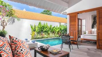 A poolside area with a white wall, a wooden door, and a chair.