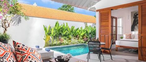 Un espace aménagé au bord de la piscine, avec un mur blanc, une porte en bois et une chaise.