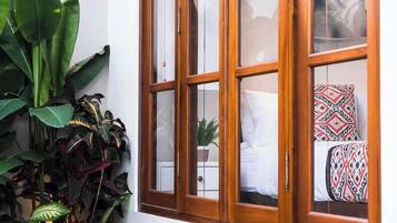 A room with a wooden-framed window, a small pool, and various plants.