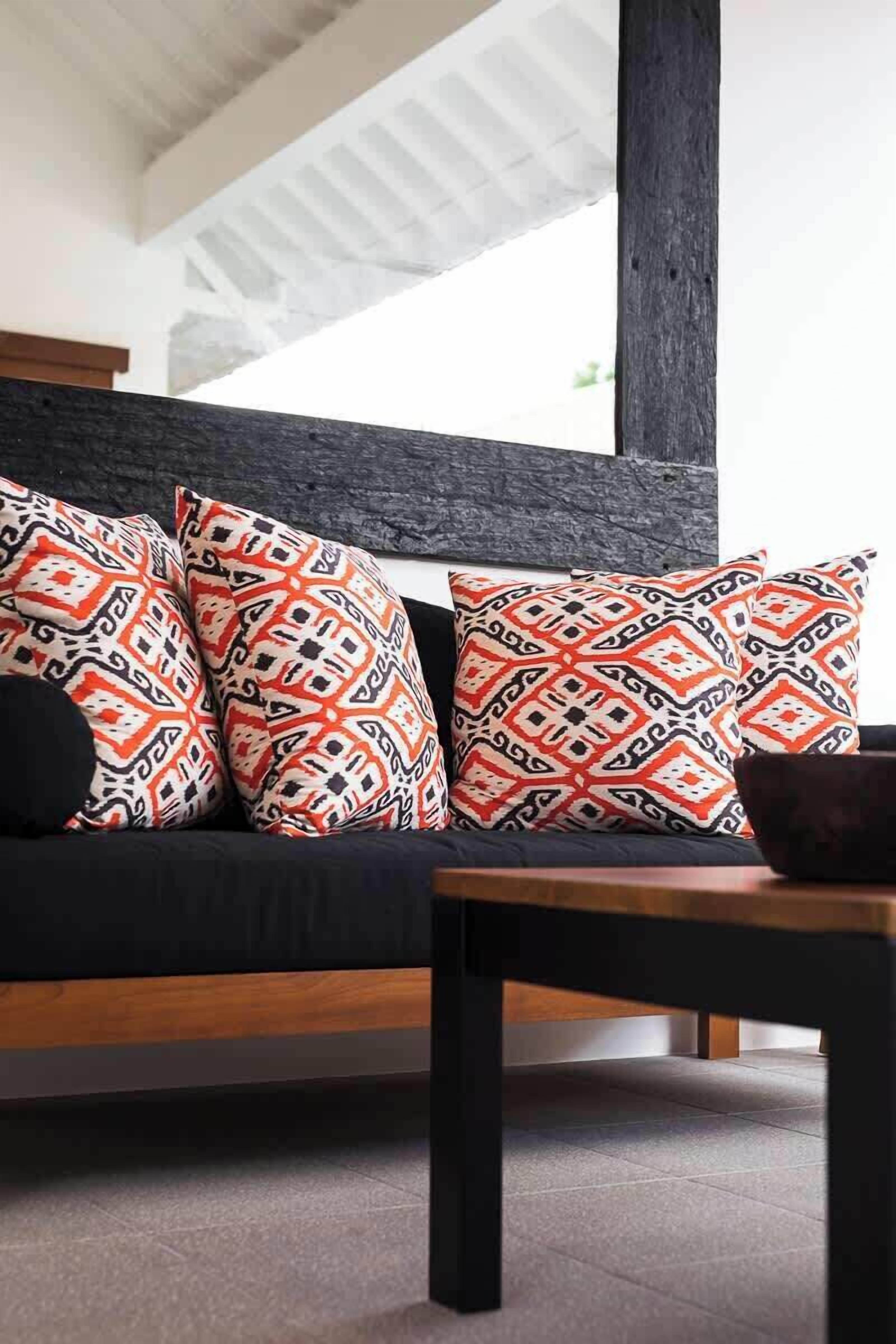 A modern living room with a dark-colored sofa, patterned cushions, and a wooden coffee table.