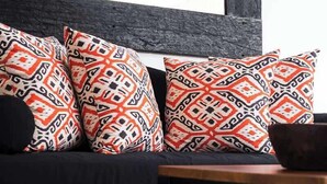 A modern living room with a dark-colored sofa, patterned cushions, and a wooden coffee table. - Cute 1BR Villa 5Mins Walk to Eat Street Seminyak (Seminyak)