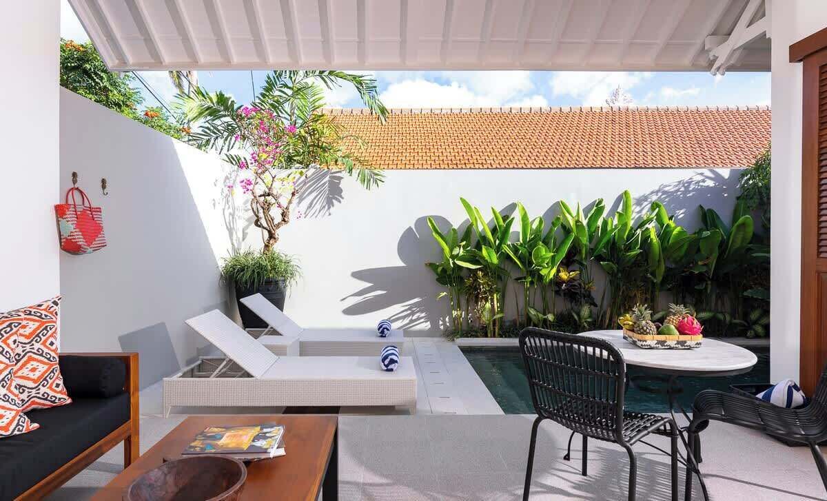 A modern outdoor patio with a pool, lounge chairs, and a dining area.