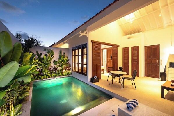 A modern house with a swimming pool, wooden doors, and a dining area.