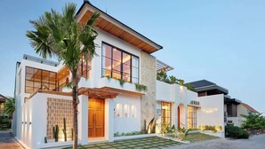 A modern two-story house with a stone facade, large windows, and a well-maintained garden.