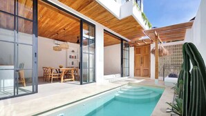 A modern house with a swimming pool, large glass doors, and a wooden ceiling.