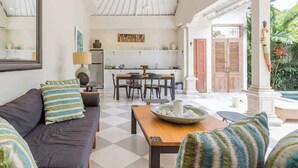 A spacious living area with a sofa, a dining table, and a kitchen in the background.