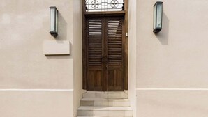A wooden double door with shutters, a set of stone steps leading up to it, and two wall-mounted lanterns on either side.