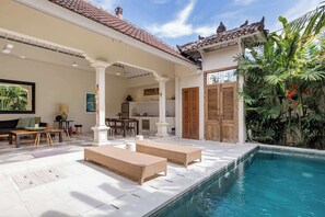 A poolside area with lounge chairs, a kitchen in the background, and tropical plants. - Unwind at Seminyak Pool Villa 1Min Walk to Center (Kerobokan Kelod)
