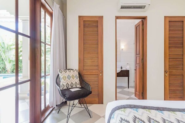 Una habitación con una cama, una silla y dos puertas de madera.