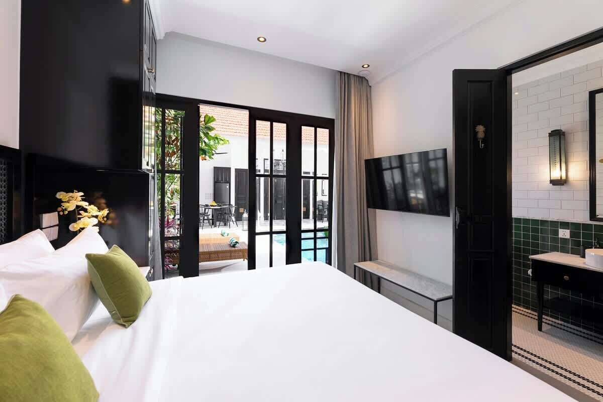 Une chambre d’hôtel moderne dotée d’un grand lit, d’un téléviseur fixé au mur et offrant une vue sur l’espace extérieur de la piscine.