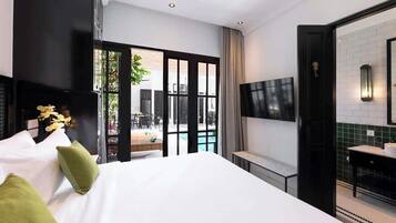 Une chambre d’hôtel moderne dotée d’un grand lit, d’un téléviseur fixé au mur et offrant une vue sur l’espace extérieur de la piscine.