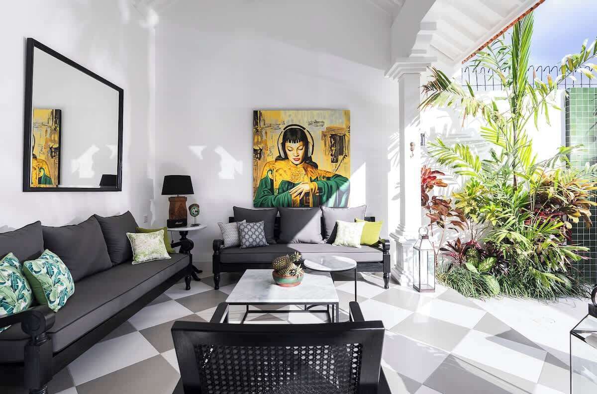 Un salon moderne avec un canapé noir, une table basse et un grand tableau accroché au mur.
