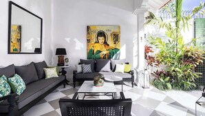 A modern living room with a black sofa, a coffee table, and a large painting on the wall. - 2BR Villa Martini 1 Spacious Walk to FINNS Beach (Dalung)