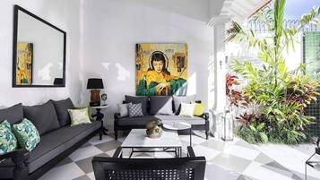 Un salon moderne avec un canapé noir, une table basse et un grand tableau accroché au mur.