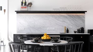 A modern kitchen with a marble countertop, black chairs, and a fruit bowl. - 2BR Villa Martini 1 Spacious Walk to FINNS Beach (Dalung)
