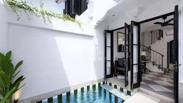 Un espace piscine intérieur moderne, avec un sol à carreaux, une petite piscine et un escalier menant à un deuxième niveau.